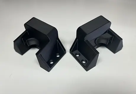 A pair of black plastic brackets sitting on top of a table.